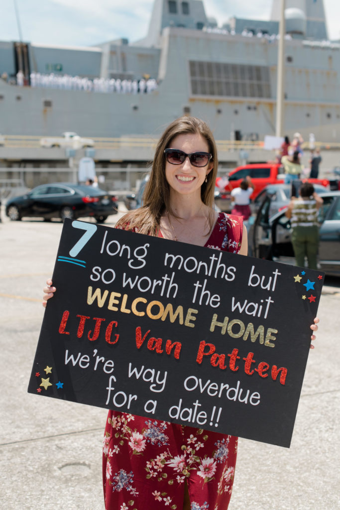 military wife holds a welcome home sign