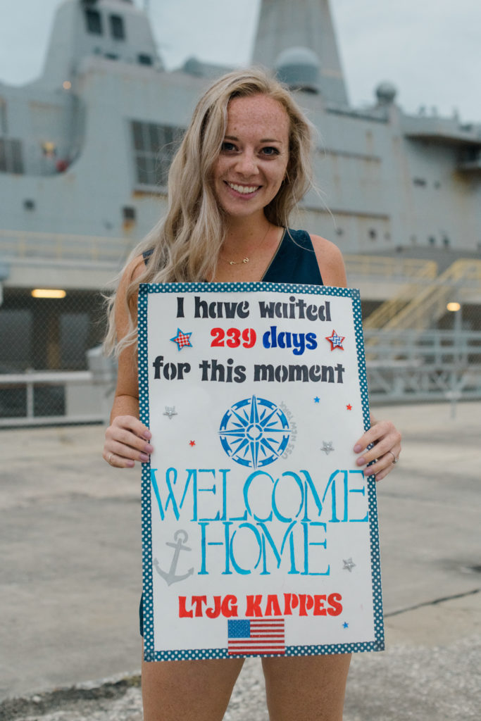 military wife holds welcome home sign at military homecoming