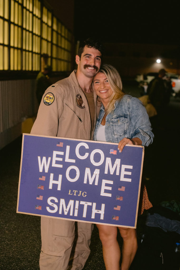 military couple holding their homecoming sign