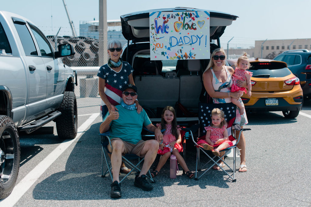 family waits by there car during a covid19 navy homecoming